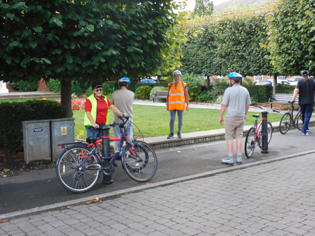 Instructors and patients standing with bicycles in a green space